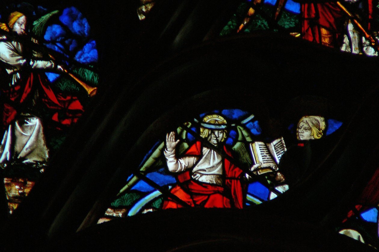 Vinduet med vestrosen viser en scene fra Åbenbaringens Bog: en engel (på en regnbue), der giver Johannes en åben bog (10:1,8). af French School