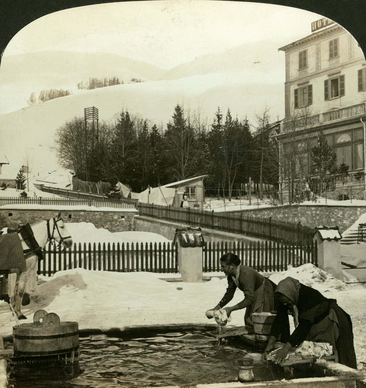 Kvinder vasker tøj ved den offentlige springvand midtvinter, Zuoz, Schweiz af H. C. White