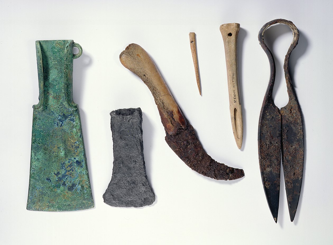 Udvalg af værktøj: L-R: bronzeøkse fra tidlig jernalder med bøjede vinger; senere jernøkse; kniv med knoglehåndtag; knogle nål; ben syl; jernstænger af Iron Age