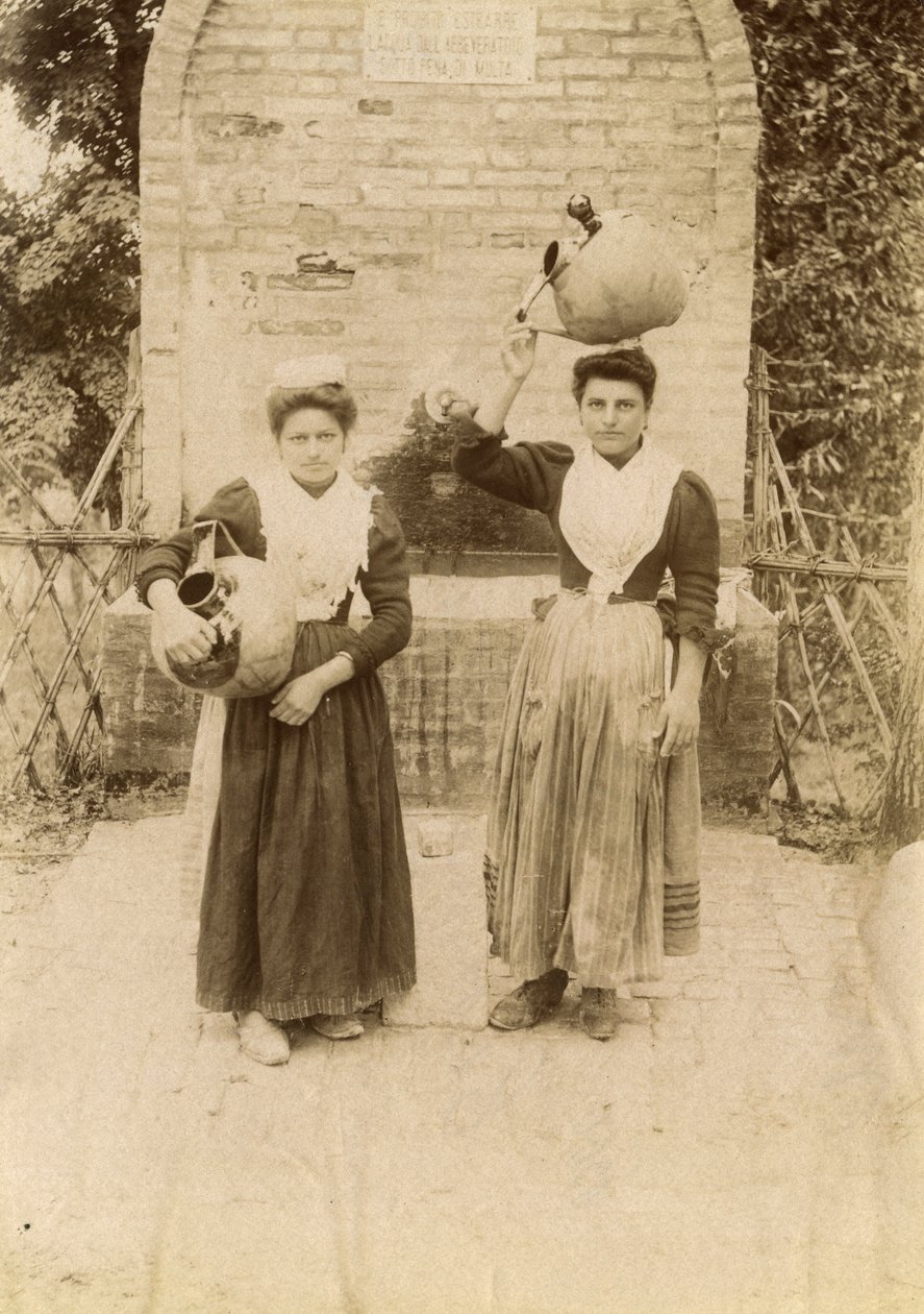To unge kvinder iført traditionelt tøj og med terrakottakrukker nær en brønd, Marche, Italien, ca. 1910 af Italian Photographer