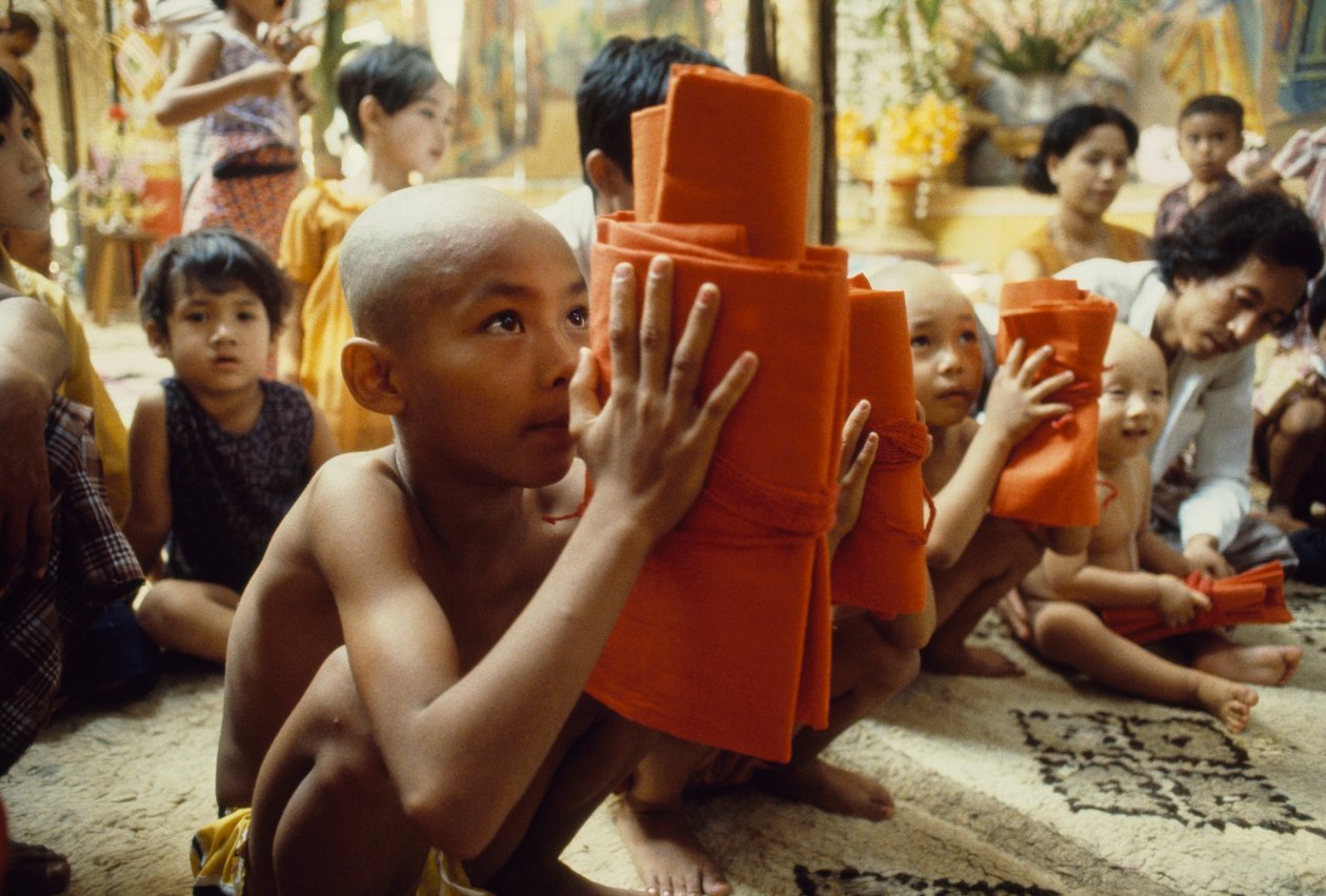 En ung dreng med barberet hoved får sit munketøj. Mandalay, Burma. af James L Stanfield