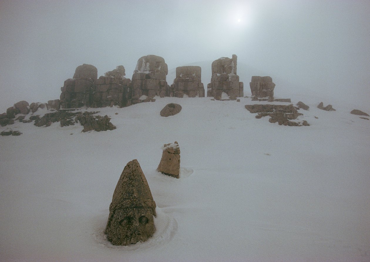 Statue af en gud kigger op over et tæppe af sne ved Nemrud Dagh. Nemrud Dagh, Tyrkiet. af James L Stanfield