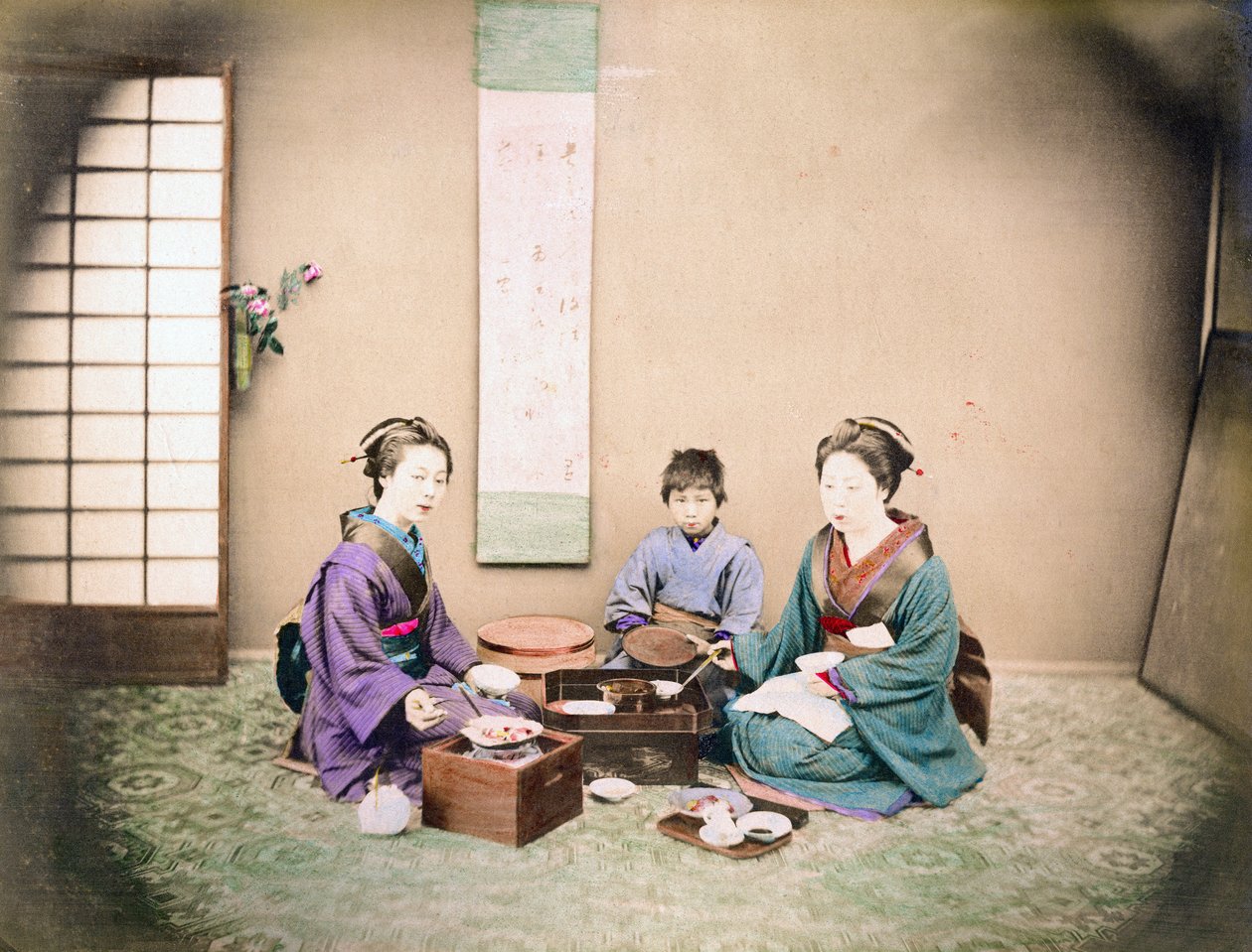 To kvinder og et barn spiser frokost, siddende på en måtte, ca. 1890 (håndfarvet foto) af Japanese Photographer