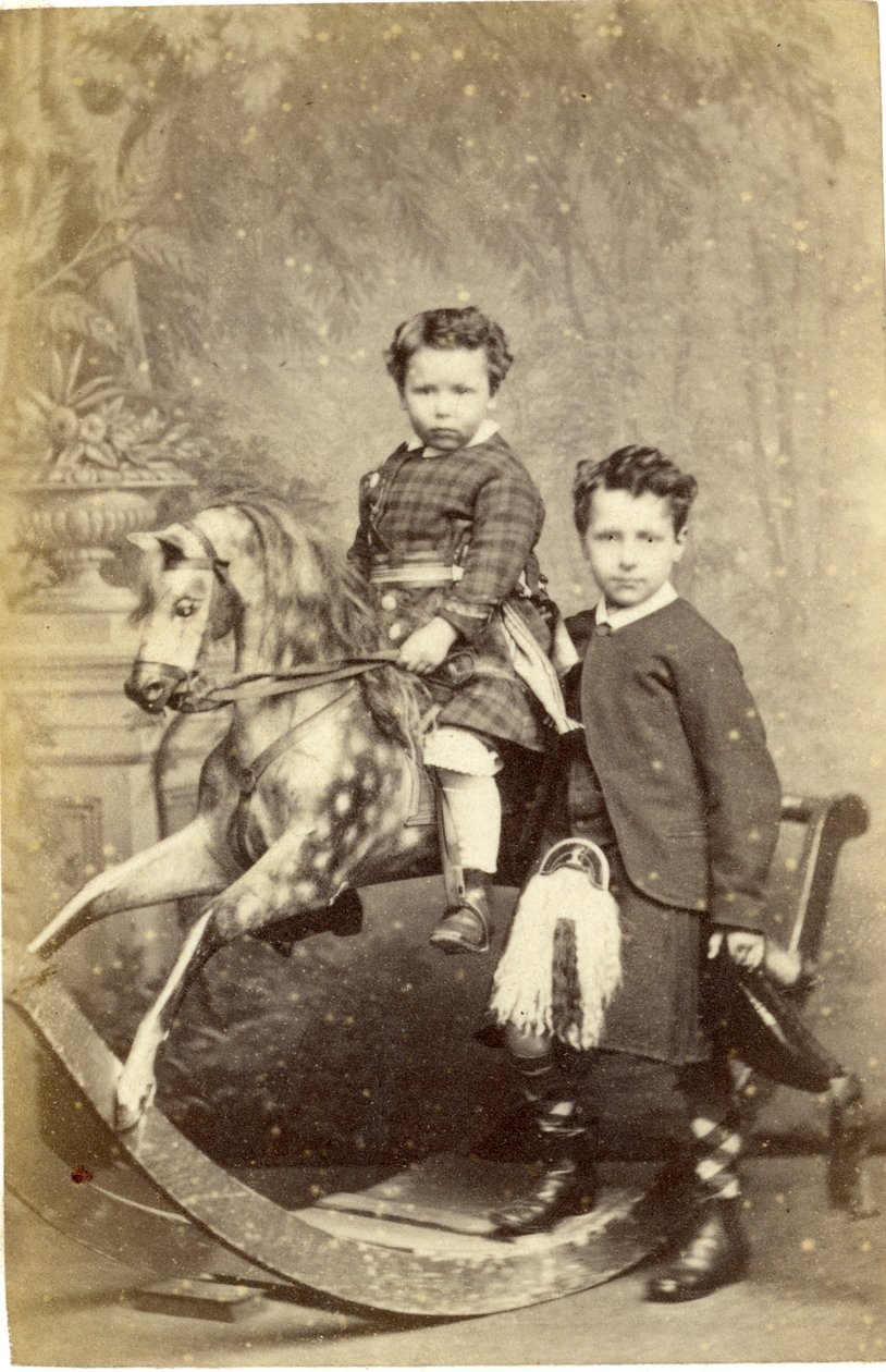 Ung pige på gyngehest med ung dreng i kilt stående, 1860