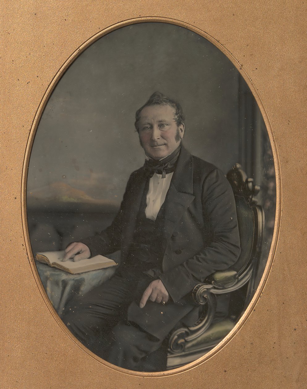 Siddende mand peger på en passage i en åben bog, 1850