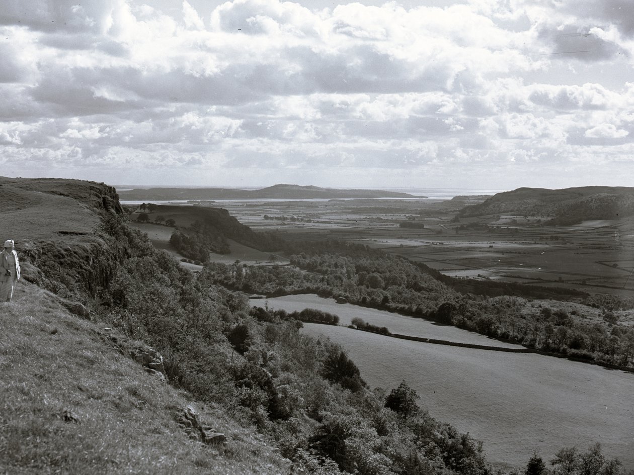 En dame står på en bjergskråning og kigger ud over landskabet ved Scout Scar. af Joseph Hardman