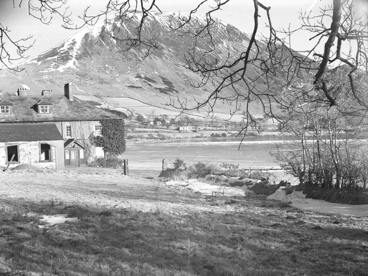 The Anglers Hotel i Ennerdale med træer i forgrunden og den frosne sø og de snedækkede fjelde bagved af Joseph Hardman