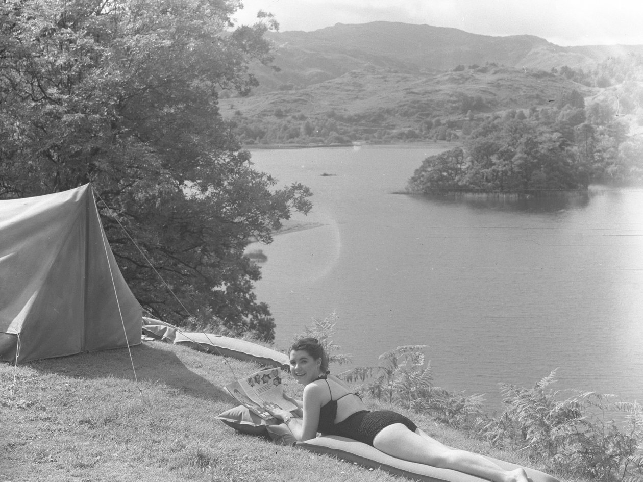 Udsigt til ung kvinde iført badedragt og liggende på en lilo, sø i baggrunden af Joseph Hardman