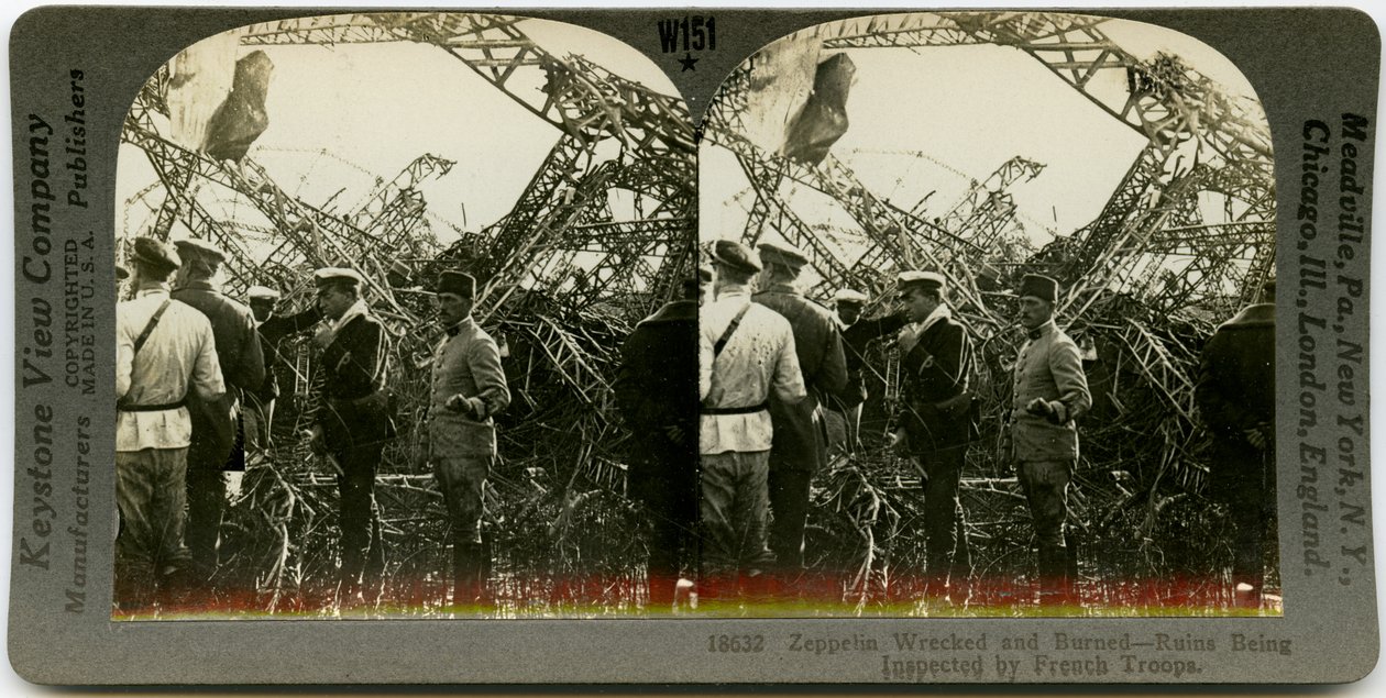 Horisontalt sepia -stereokort, der viser en gruppe uniformerede mænd, der undersøger vragdele af en zeppelin. Keystone Stereograf nummer 18632. Titlen lyder af Keystone View Company
