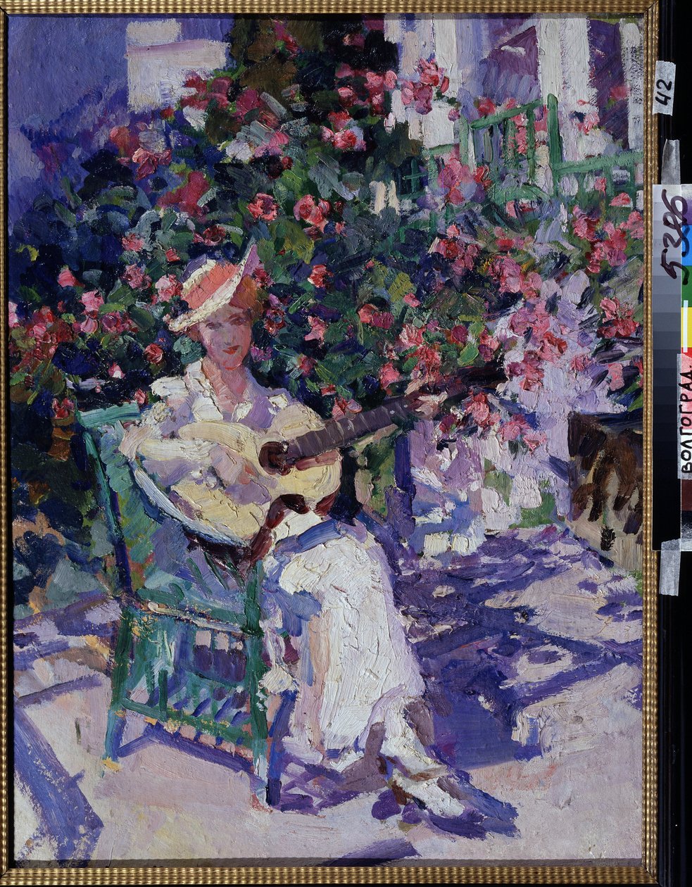 In Crimea (På Krim). En ung kvinde i en let, let kjole, der sidder på en havestol, foran en blomstrende lund, spiller på guitar, midt om sommeren i kystregionen ved Krimbugten. Maleri af Konstantin Alexeyevich Korovin (Constan af Konstantin Alekseevich Korovin