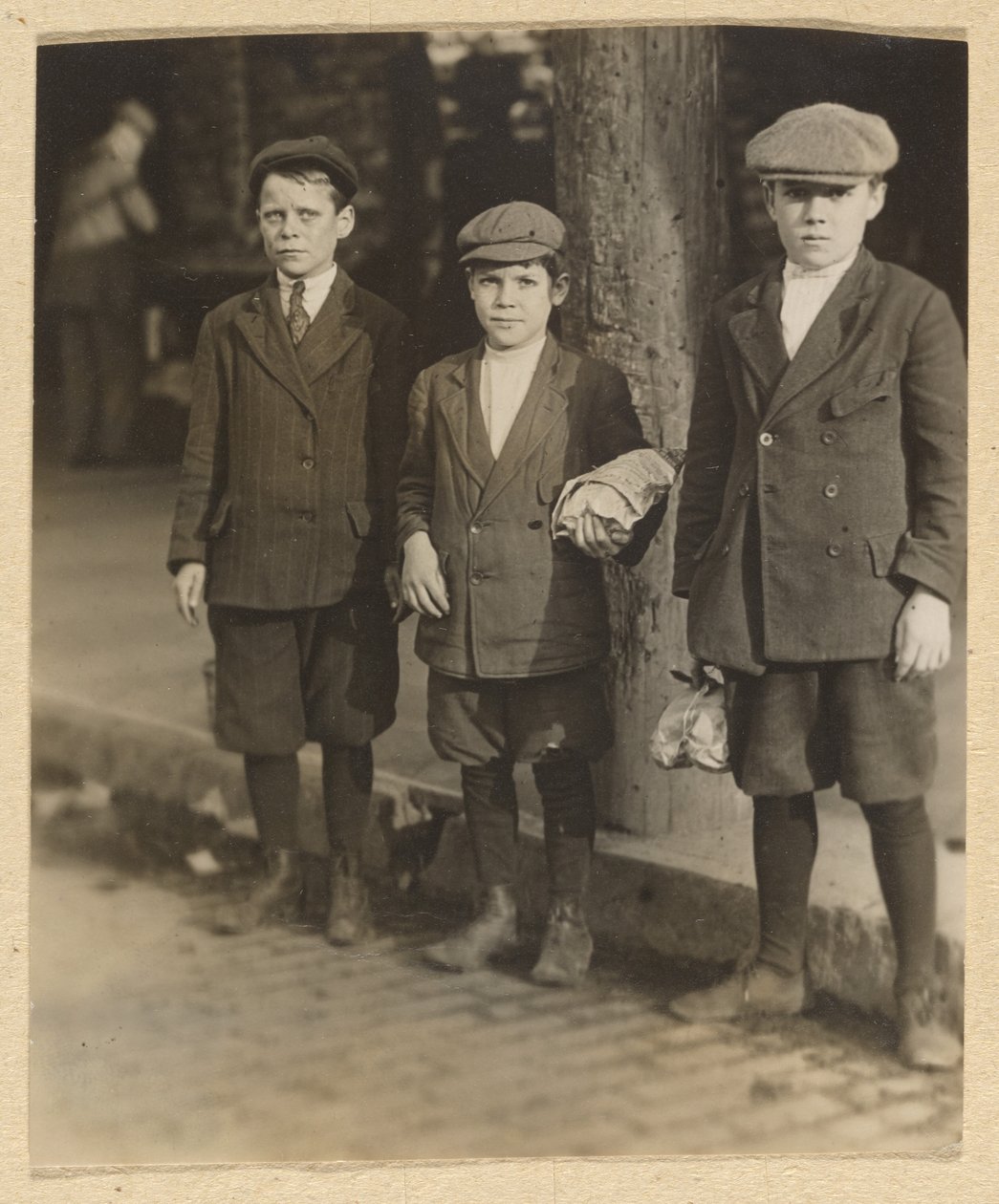 [Tre drenge på City Street i knickers og kasketter]. af Lewis W. Hine