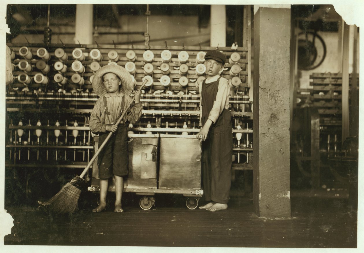 12-årige doffer Ronald Webb og 7-årige Frank Robinson, søn af cardroom boss, som fejer og fjerner (rydder hele spoler) ved Roanoke Cotton Mills, Virginia, 1911 af Lewis Wickes Hine