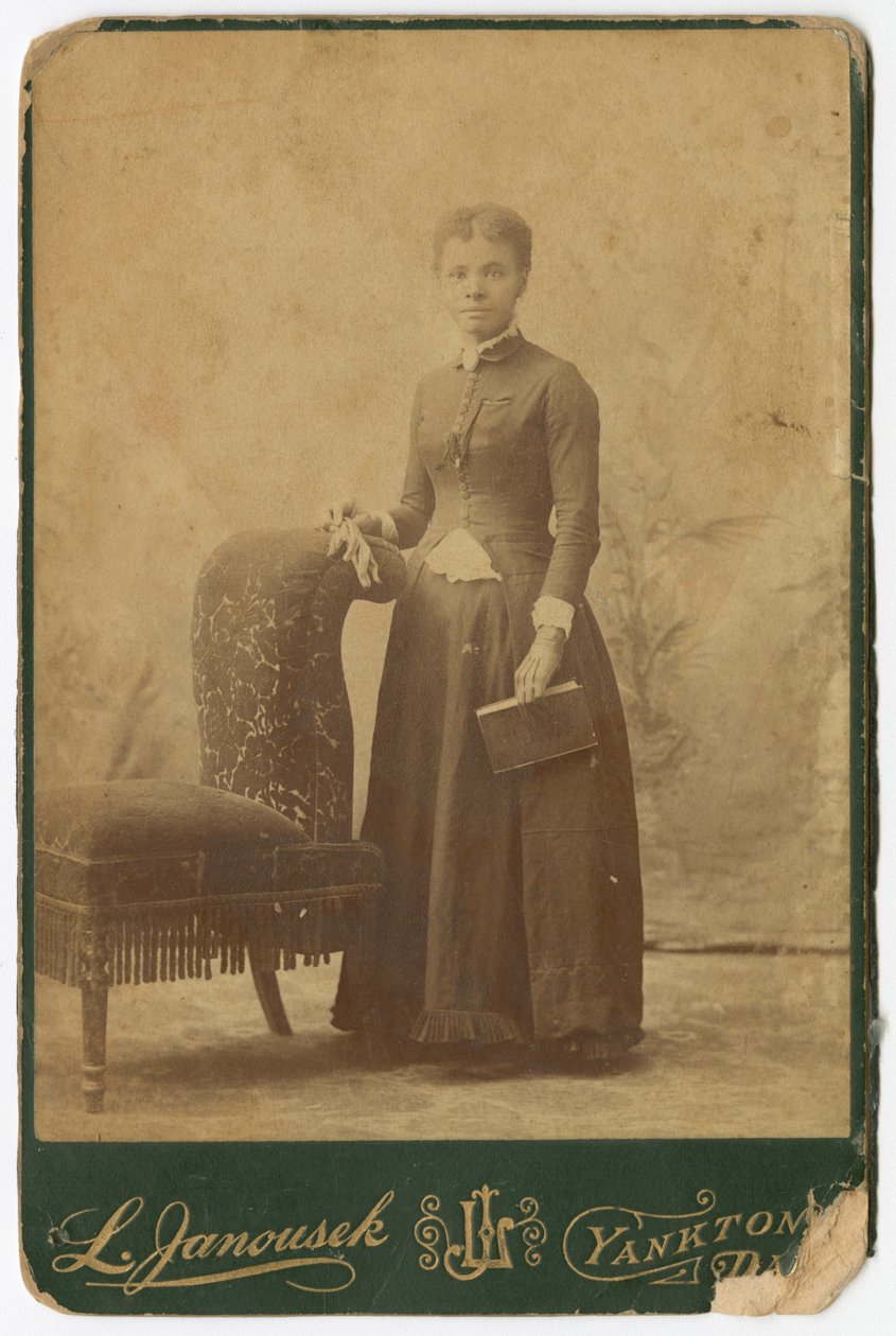 Fotografi af en kvinde, der står ved siden af en stol og holder en bog, slutningen af det 19. århundrede. af Louis Janousek