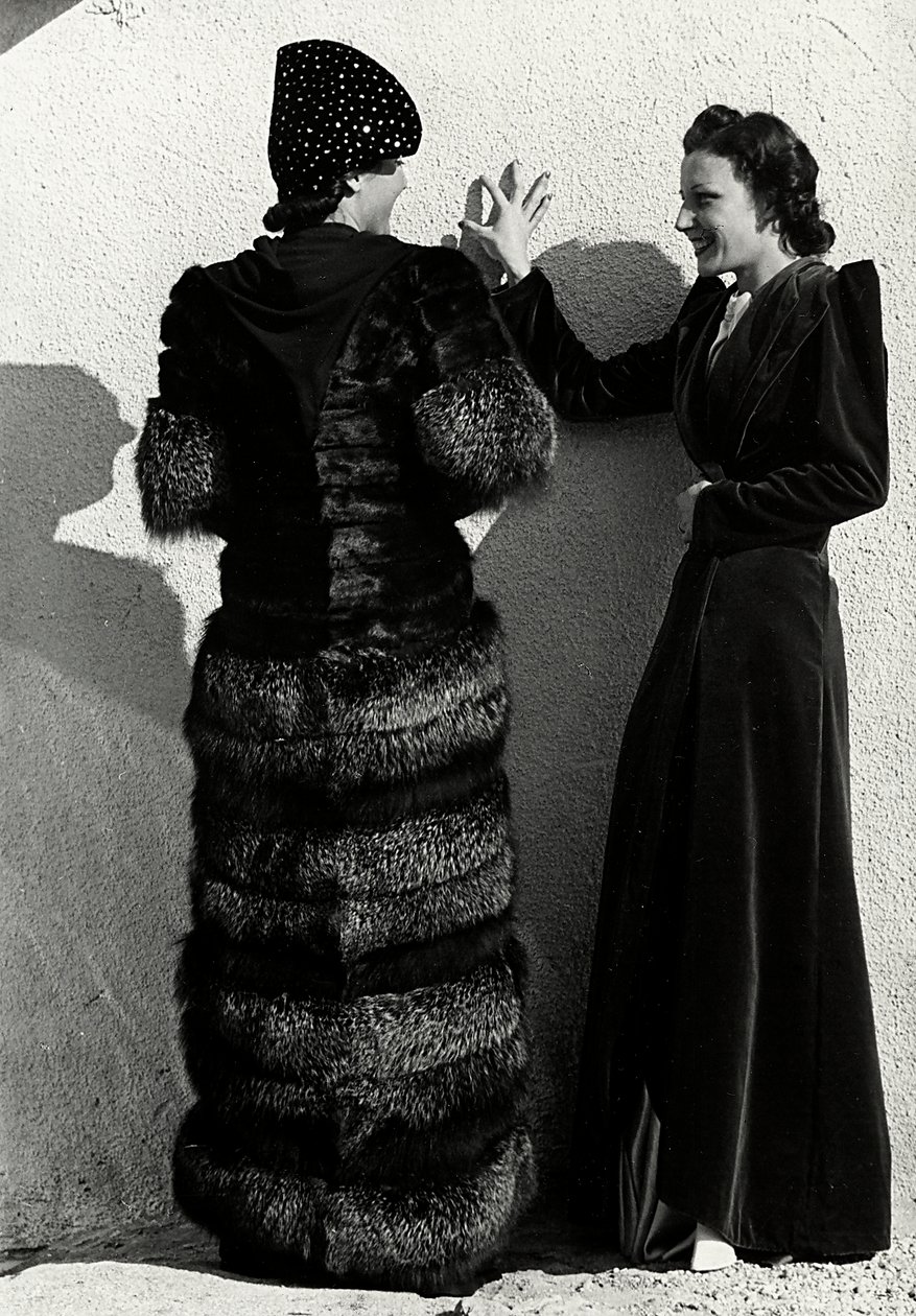 To modeller præsenterer kreationer af det italienske couture-hus "Dragoni". Den ene model set bagfra bærer en sølvrævefrakke. Den anden model er iført en lang fløjlsoverfrakke. (s/h foto) af Luis Bogino