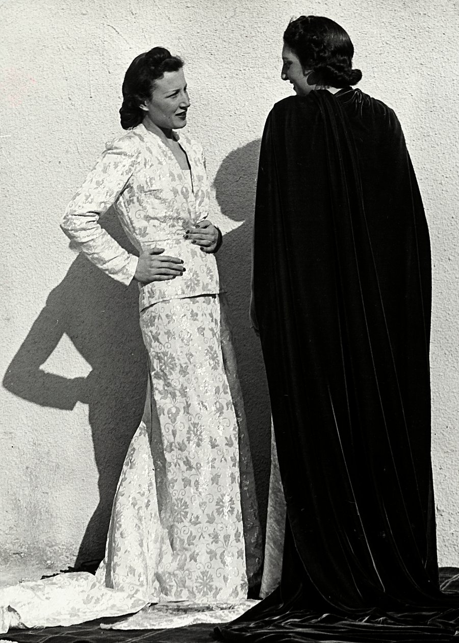To modeller præsenterer kreationer af det italienske couture-hus "Dragoni". Den ene model bærer et outfit i blemateriale bestående af en jakke og lang nederdel med tog. Den anden model, set bagfra, bærer en lang fløjlskappe. (s/h foto) af Luis Bogino