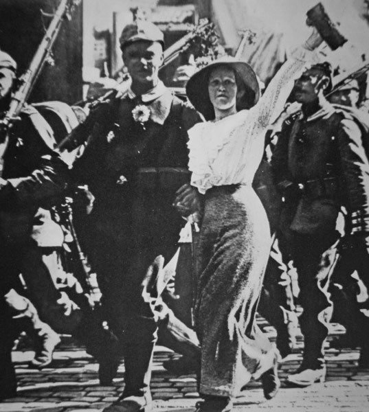 tyske tropper fra første verdenskrig, der marcherer ud i krig, deres tunikaer og rifler prydet med blomster fra den jublende folkemængde af Photographer German