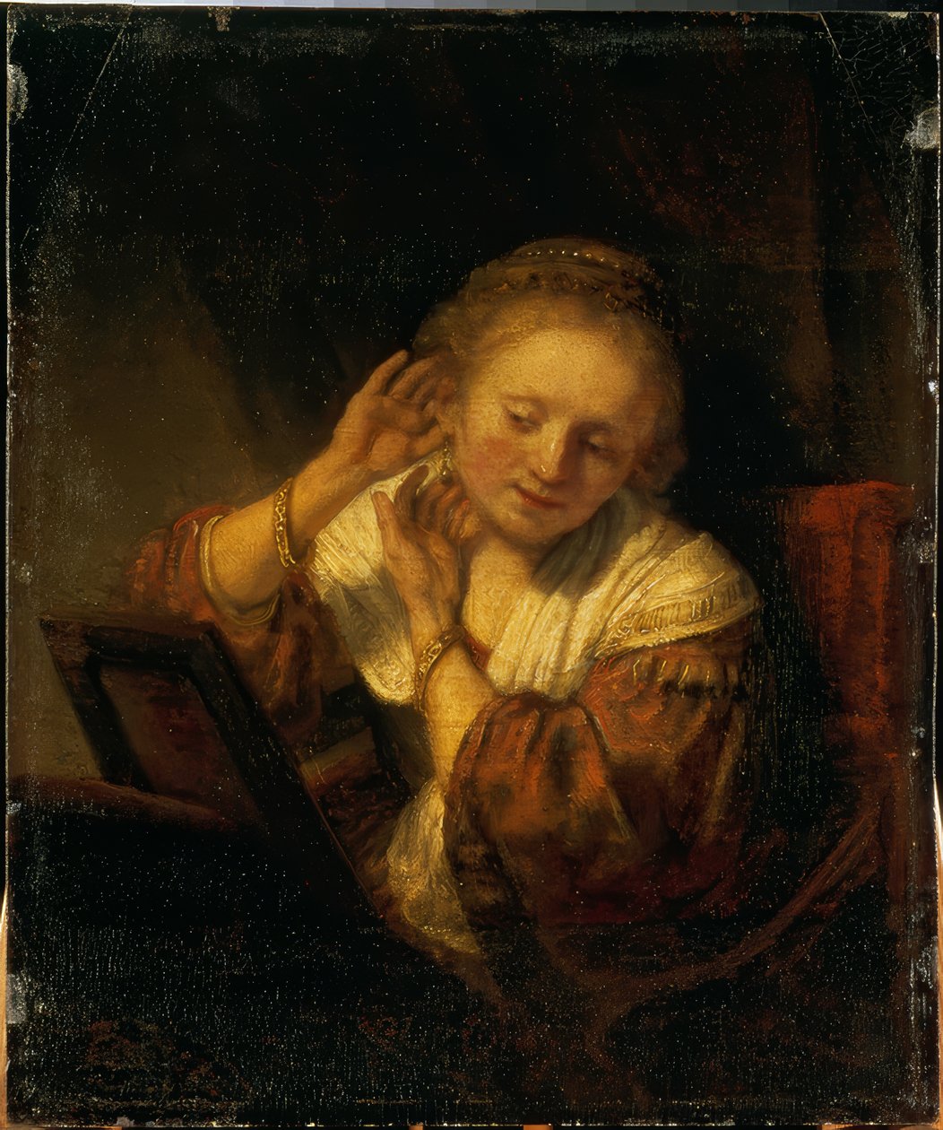 Ung kvinde pynter sig med øreringe af Rembrandt van Rijn