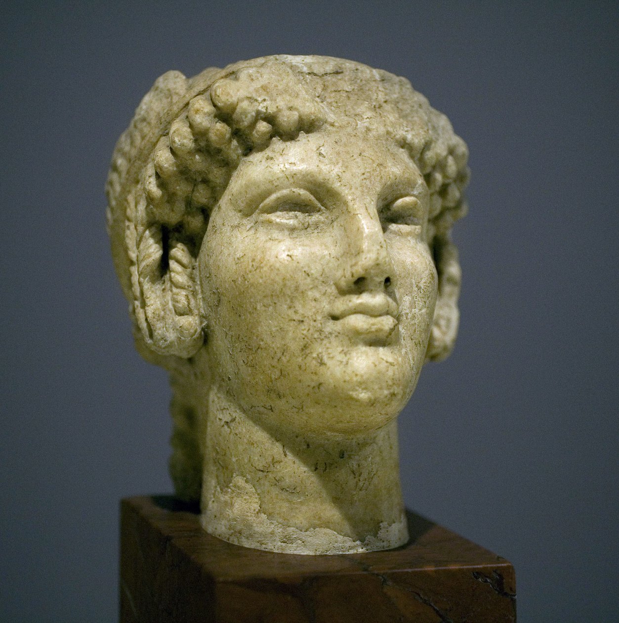 Pigehoved (Kore), skulptur fra den romerske hellenistiske periode (3. 2. århundrede efter vores æra), meget udtryksfuldt ansigt, fremtrædende kindben mod øst, smil, krøllet hår, arkaisk stil af Ionie i det 6. århundrede før vores æra, som varede længe efte af Roman