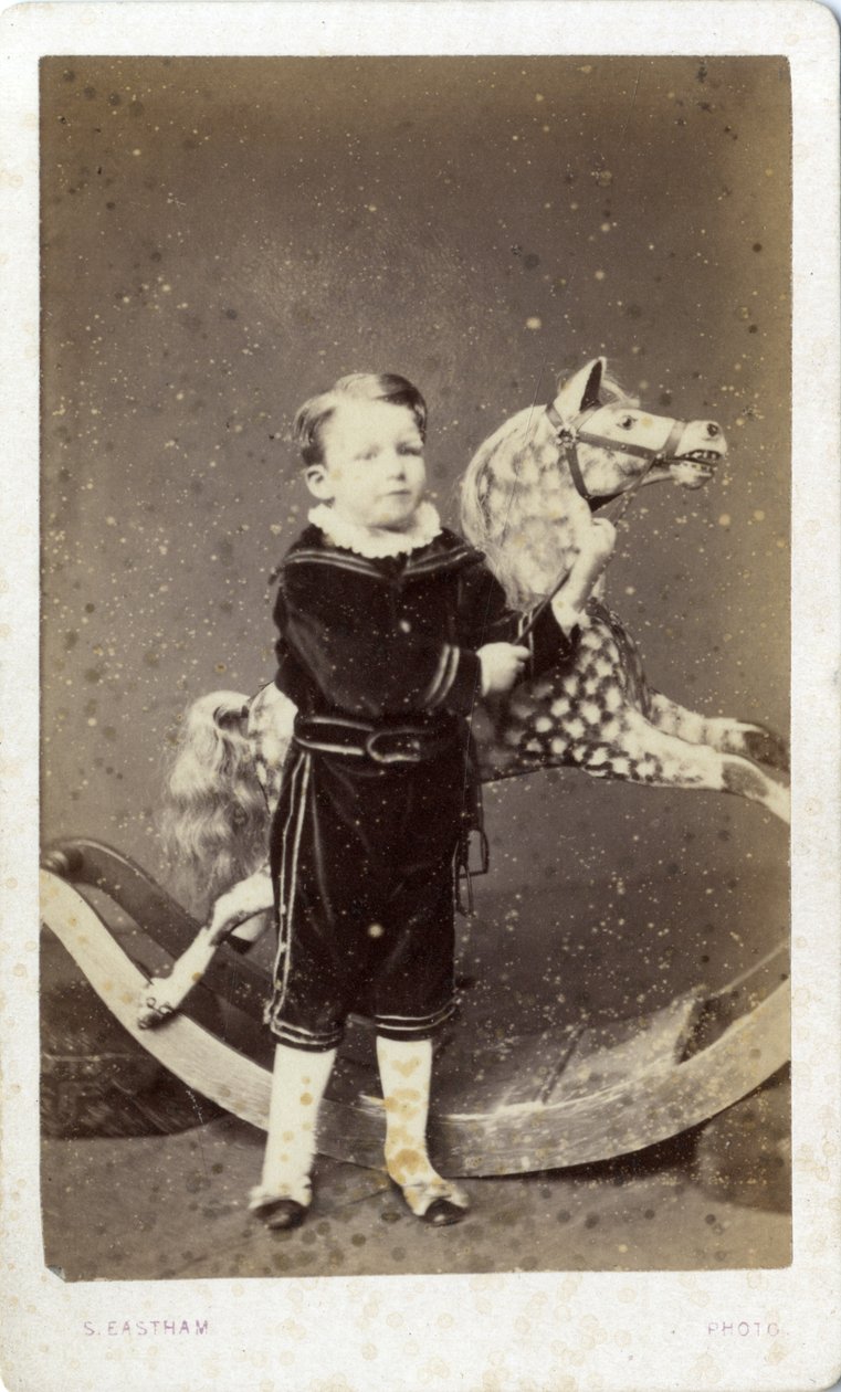 Ung dreng stående ved en gyngehest af Silas Eastham