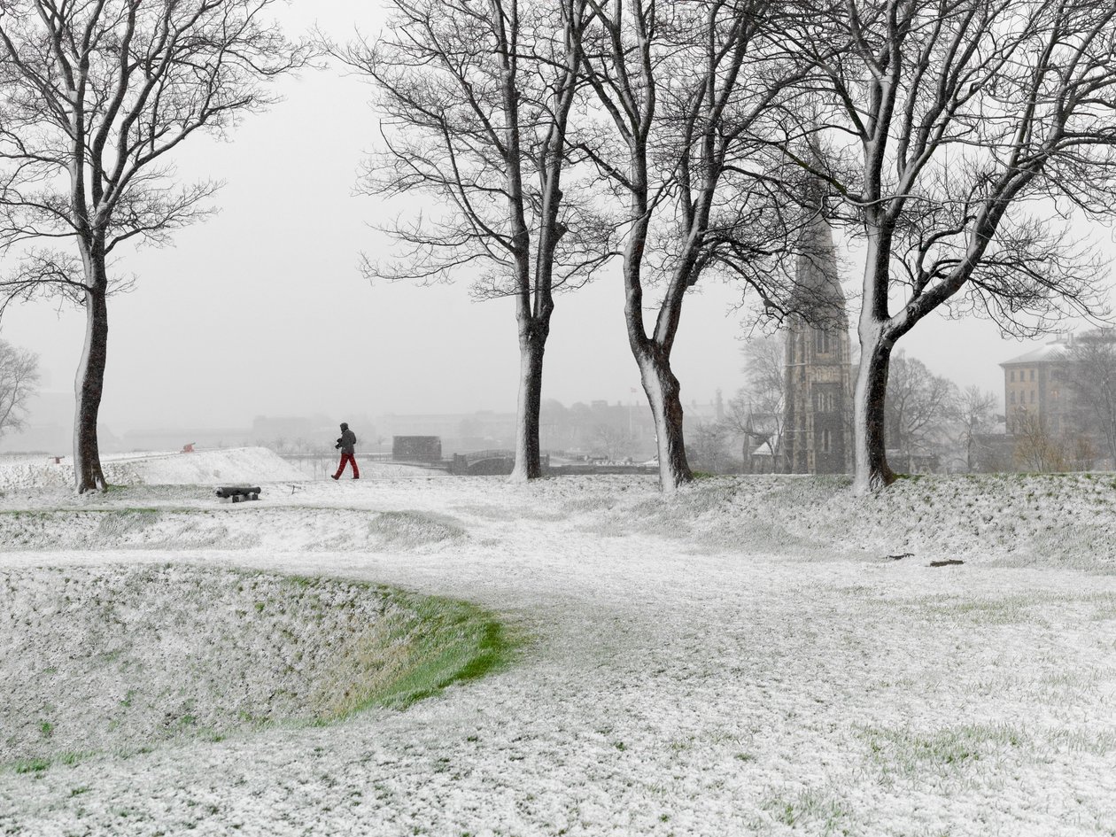 Ensom skikkelse går rundt i Københavns Befæstning i snestorm, Danmark, 2022 (foto) af Sisse Brimberg