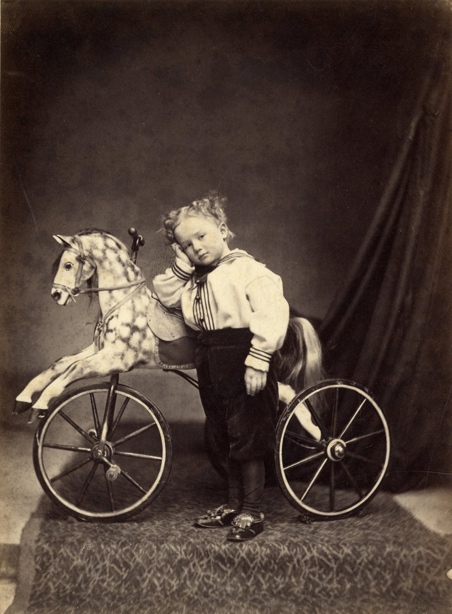 Ung dreng stående ved siden af sin hest monteret som en trehjulet cykel, 1860