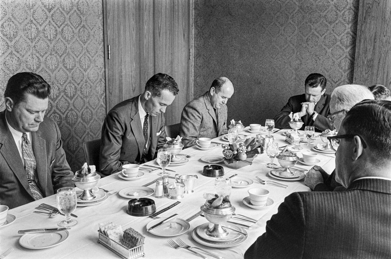 Forretningsmænd beder, før de begynder at spise frokost ved et kirkefundraisingmøde af Ted Spiegel