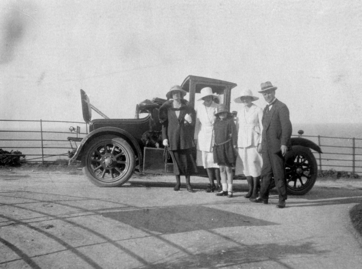En gruppe mennesker foran deres bil ved havet, c1920