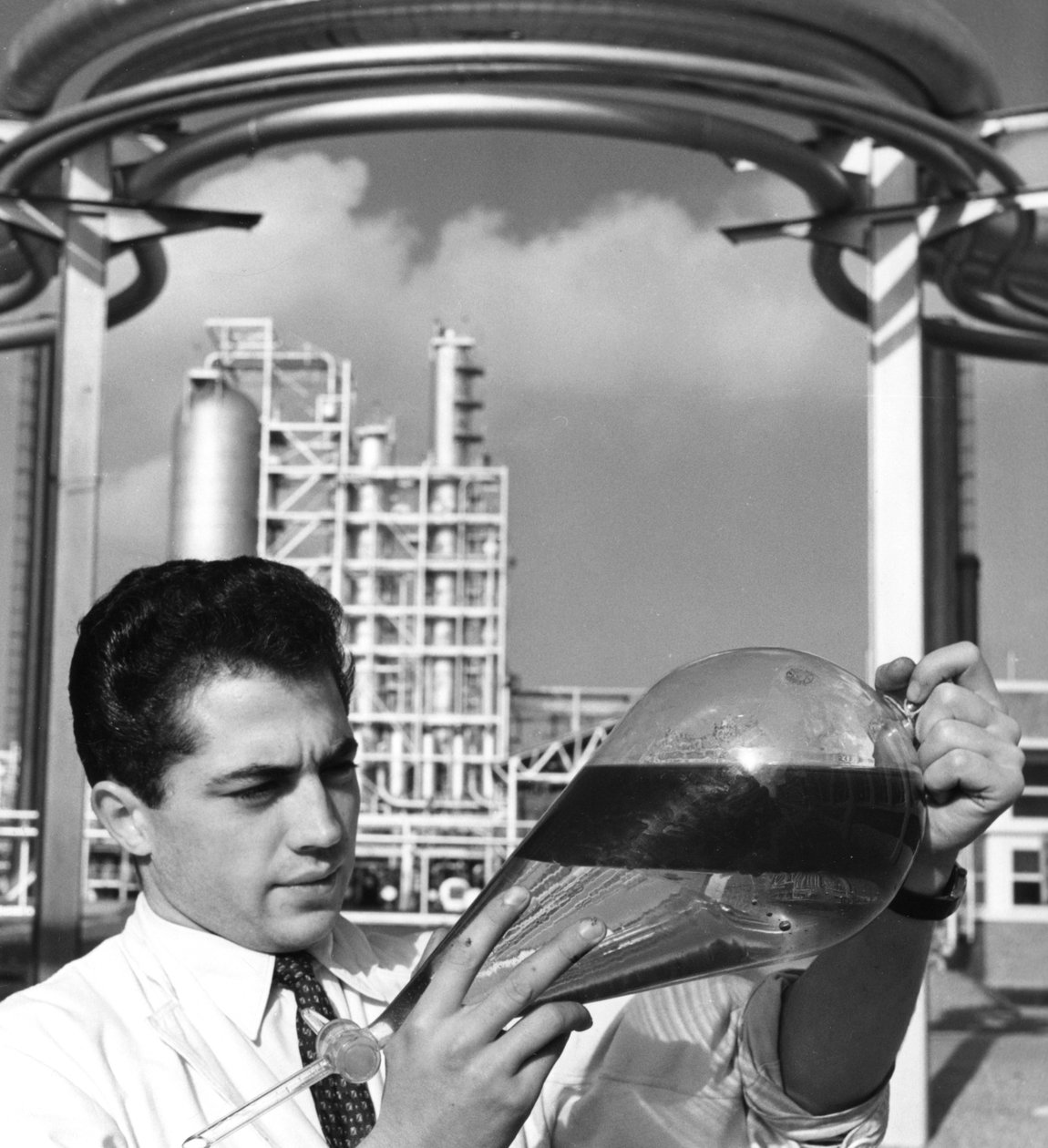 En laboratoriearbejder holder en skilletragt af olie, Dunkerque raffinaderi, Frankrig, 1950