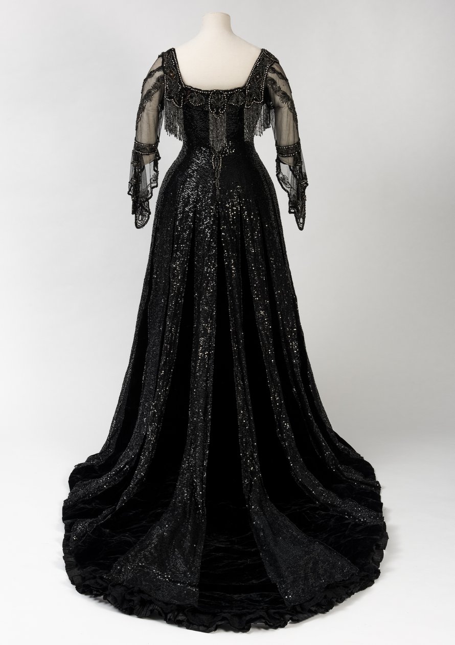 Sort aftenkjole i fuld længde båret af dronning Alexandra, med dekoration af perler og pailletter og inkorporeret dronning Alexandras signaturnavnebånd i sort silke og guld, lavet af Barolet fra Knightsbridge, London 1908-1910 (silke og fløjl) af Unbekannt