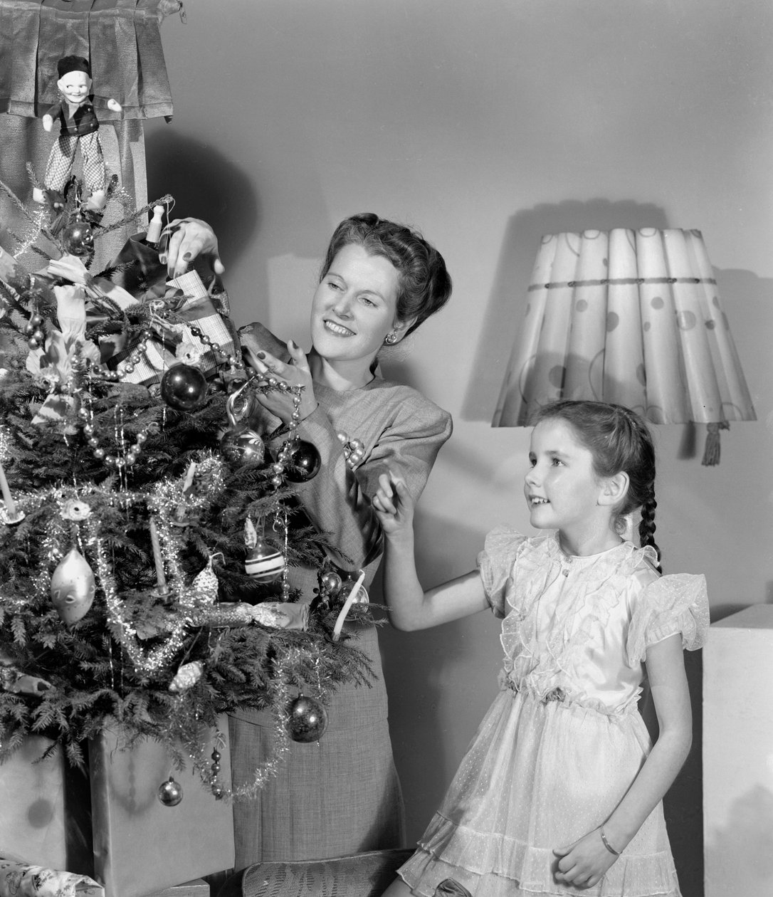 Kvinde og pige pynter et juletræ, c 1948 af Unbekannt