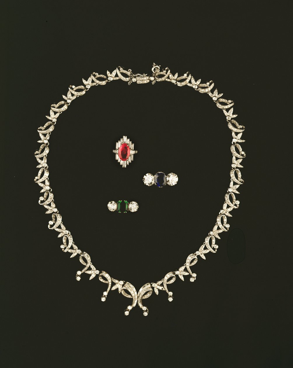 Art Deco rulle- og bladdesign halskæde; rubin og diamant baguette klynge ring; safir og diamant tre sten ring; smaragd og diamant trestensring af Unbekannt Unbekannt