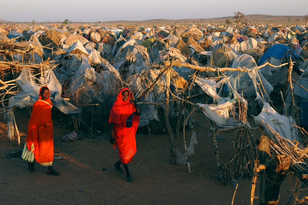 Klædt i knaldrødt tøj går kvinder gennem Otash-lejren for internt fordrevne af Unbekannt Unbekannt