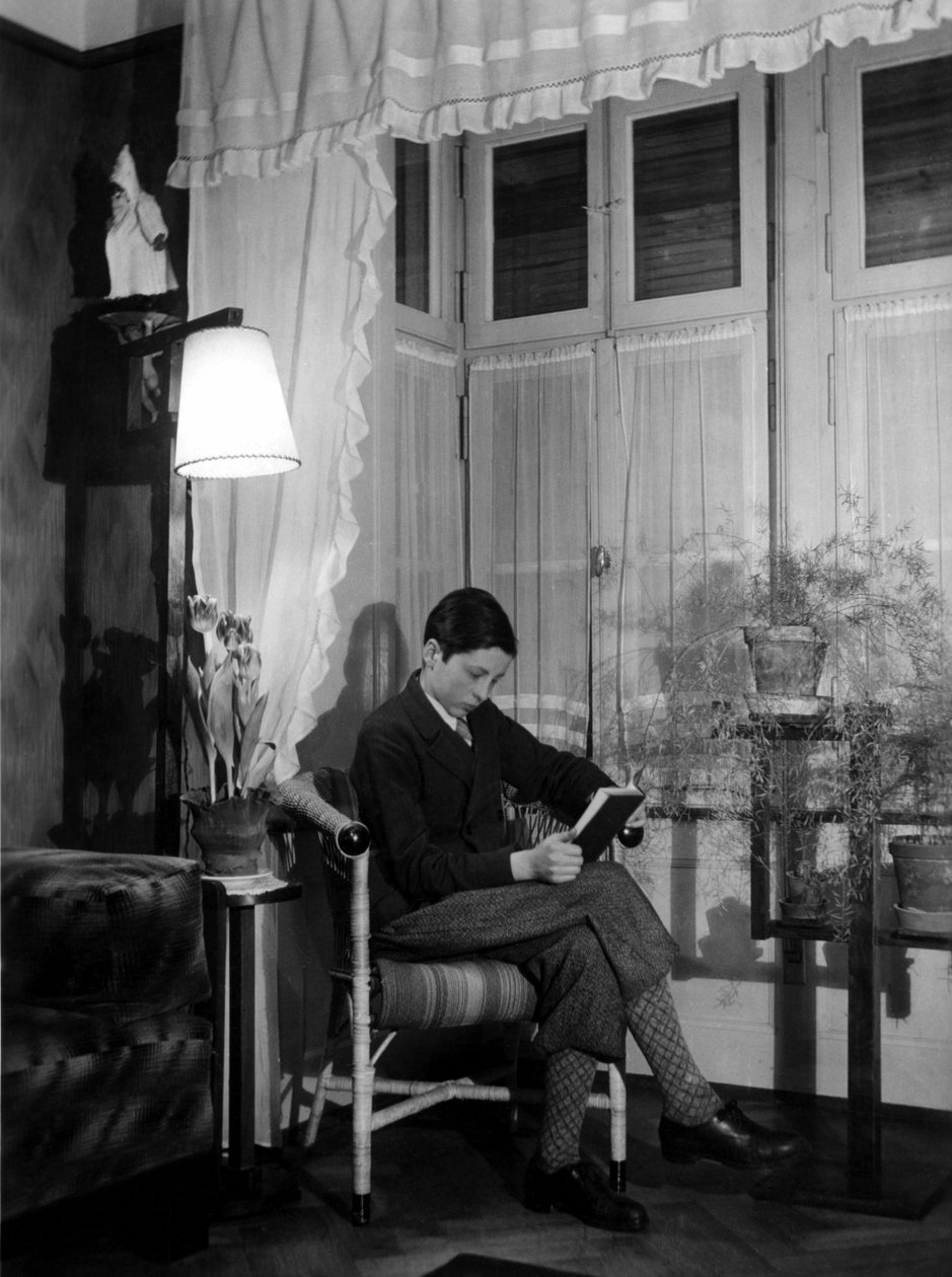 En teenager sidder i et borgerligt interiør og læser en bog, iført korte bukser og høje sokker. 1915. Historisk foto, kvinde læser, ca. 1915 af Unbekannter Künstler