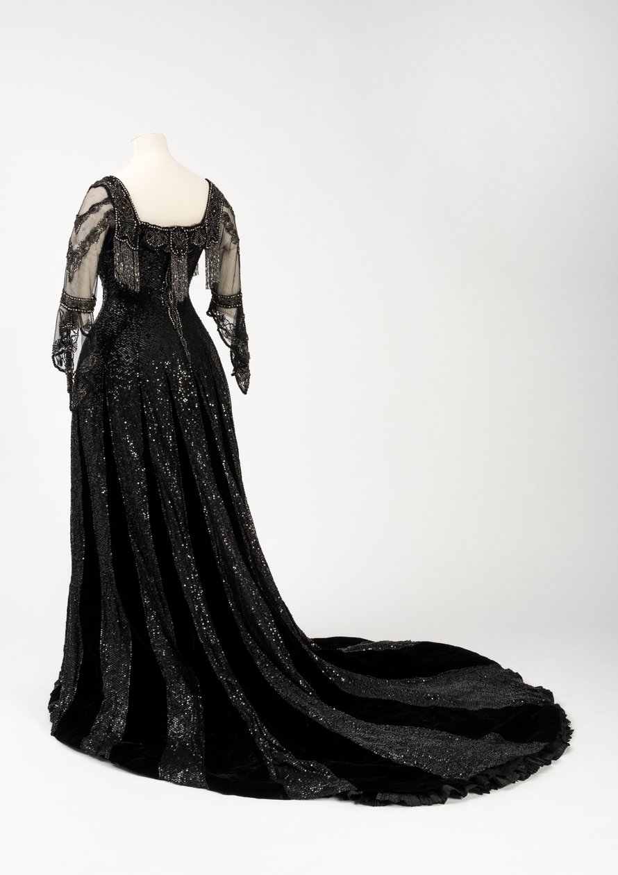 Sort aftenkjole i fuld længde båret af dronning Alexandra, med dekoration af perler og pailletter og inkorporeret dronning Alexandras signaturnavnebånd i sort silke og guld, lavet af Barolet fra Knightsbridge, London 1908-1910 (silke og fløjl) af Unbekannt