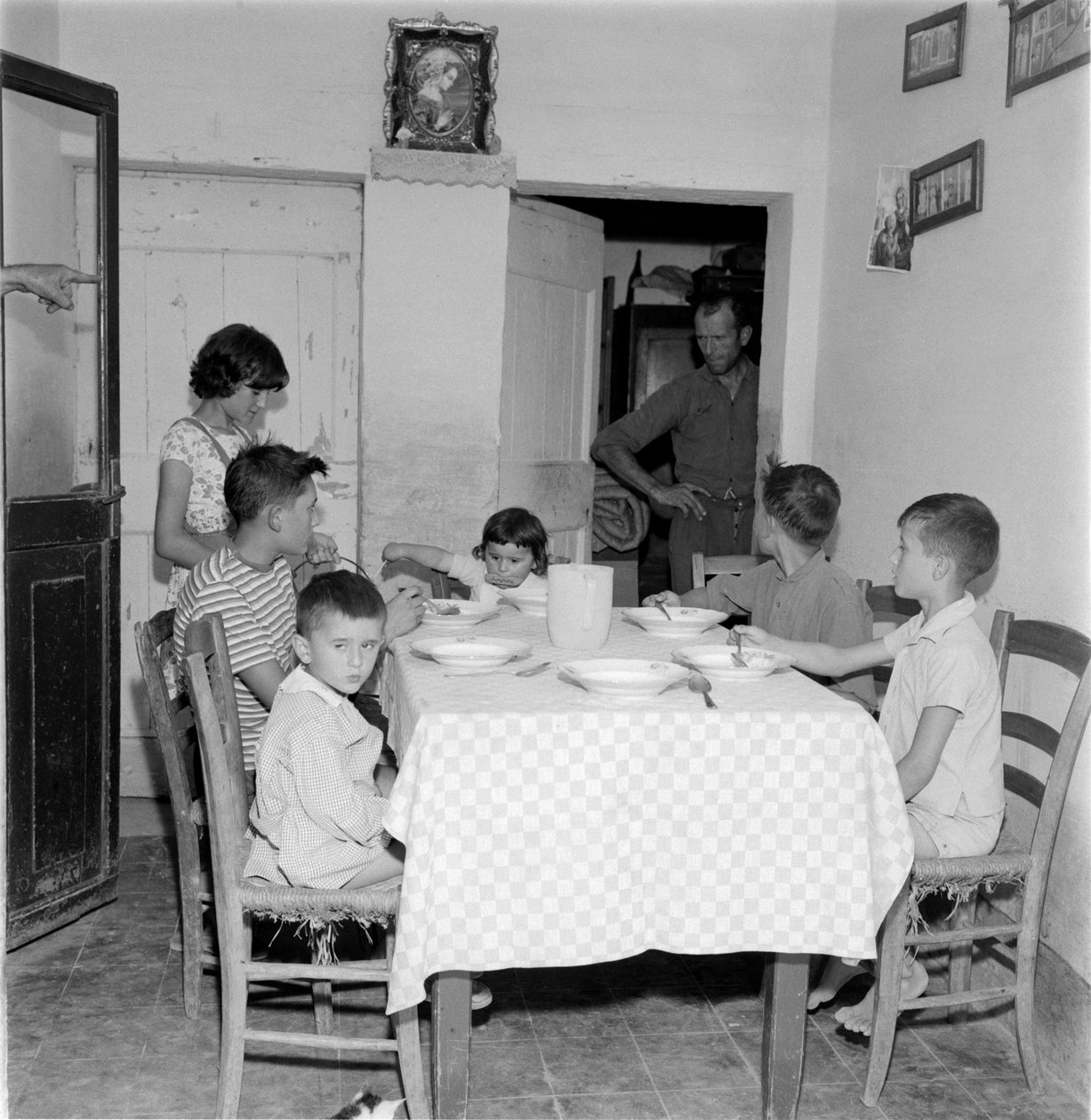 Stor familie genforenet ved bordet i spisestuen i landstedet. 1960