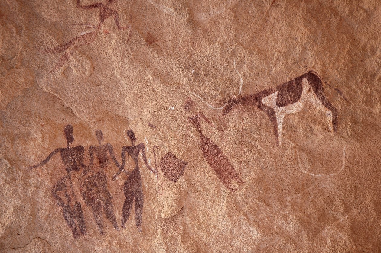 Klippekunst, forhistorie: Klippemaleri af en gruppe karakterer og en tofarvet ko med store horn i et udsmykket læ, i Uweinat-massivet, Egypten. (Periode fra 8000 til 3000 år f.Kr.). Fotografering af Unbekannt