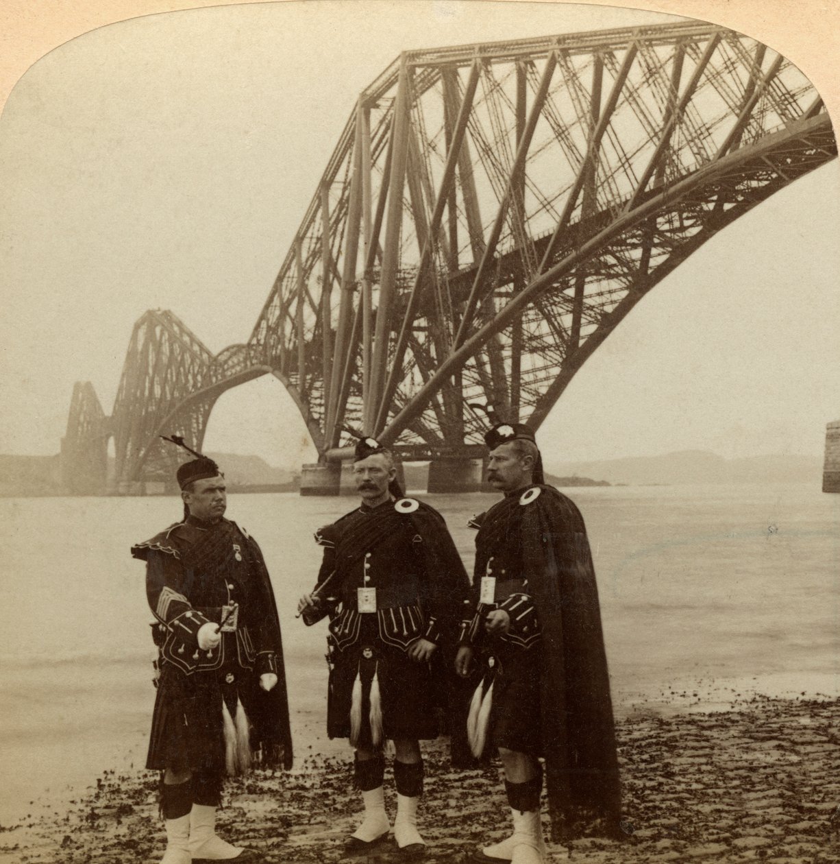 Mænd i Highland klæder sig foran Forth Bridge, Skotland. af Underwood and Underwood