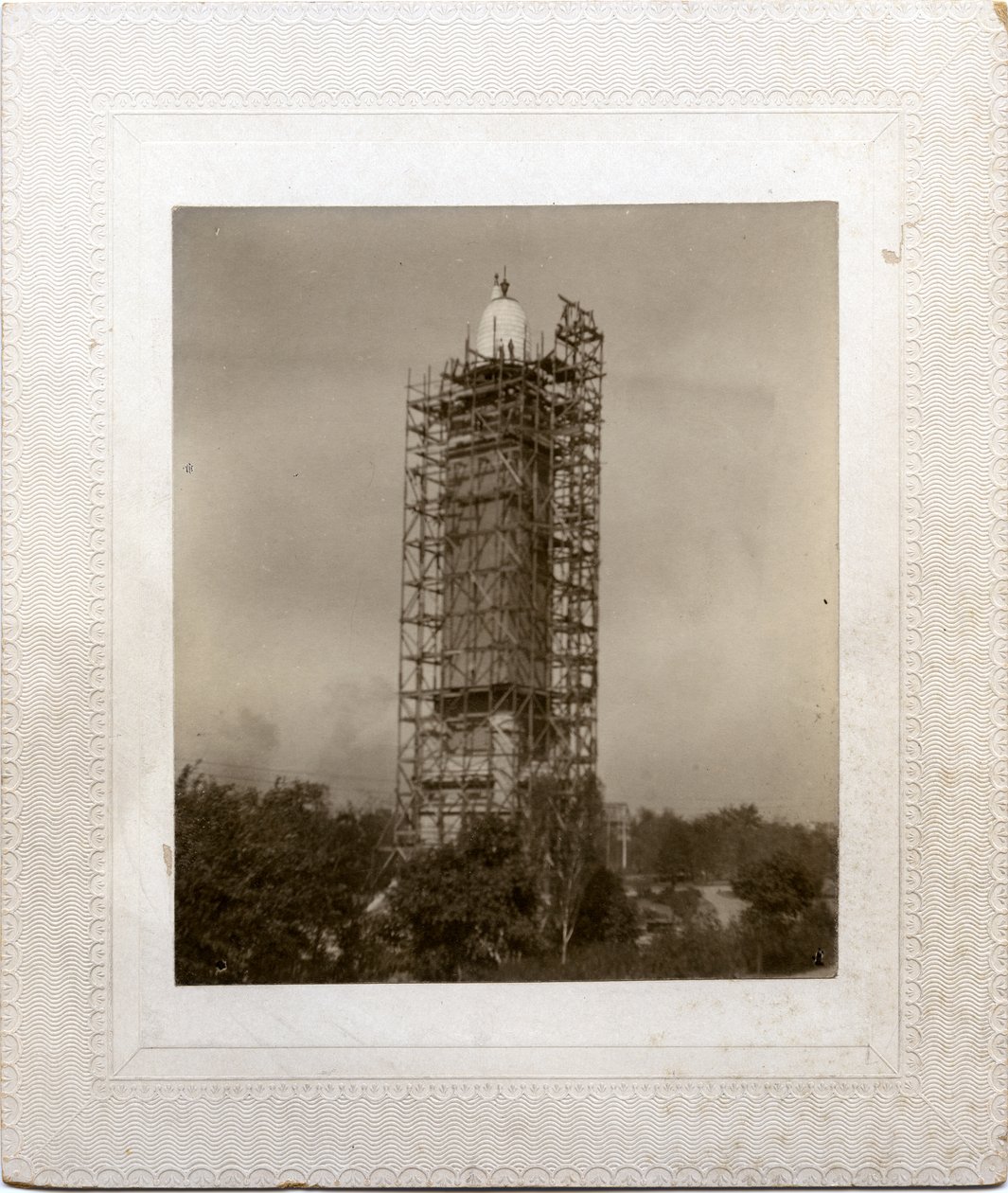 Opførelse af Compton Heights Water Tower over eksisterende standpipe, med stilladser omkring tårn og arbejder på taghøjde. af Unknown