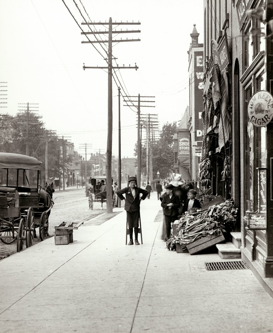 En dreng med stylter står foran F.J. Voepel Market på 4874 Easton Avenue, på det sydøstlige hjørne af Easton og Euclid. Easton blev senere kendt som Dr. Martin Luther King Drive af Unknown