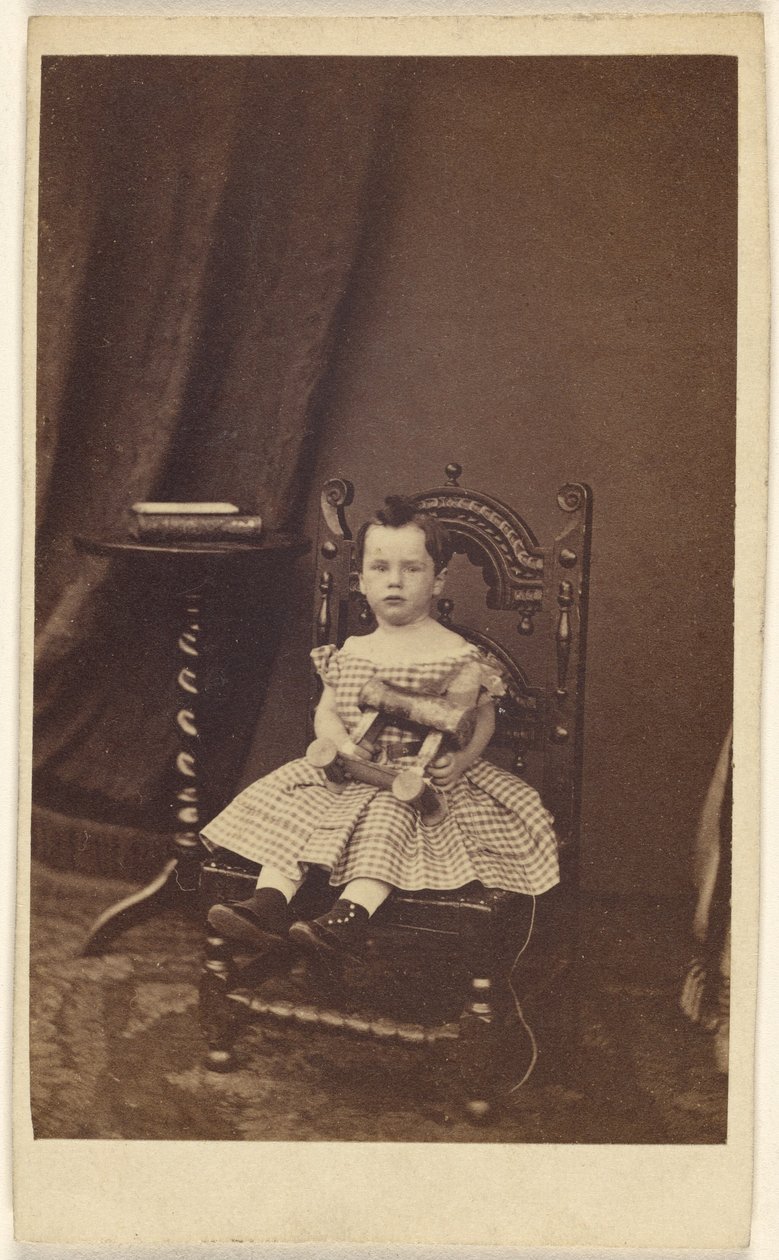 [Uidentificeret lille pige holder en legetøjshest af træ, siddende]. af Unknown artist