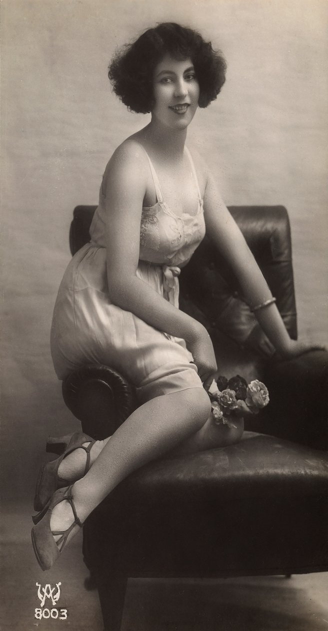 En ung kvinde poserer i sin underkjole, siddende i en lænestol af Unknown photographer