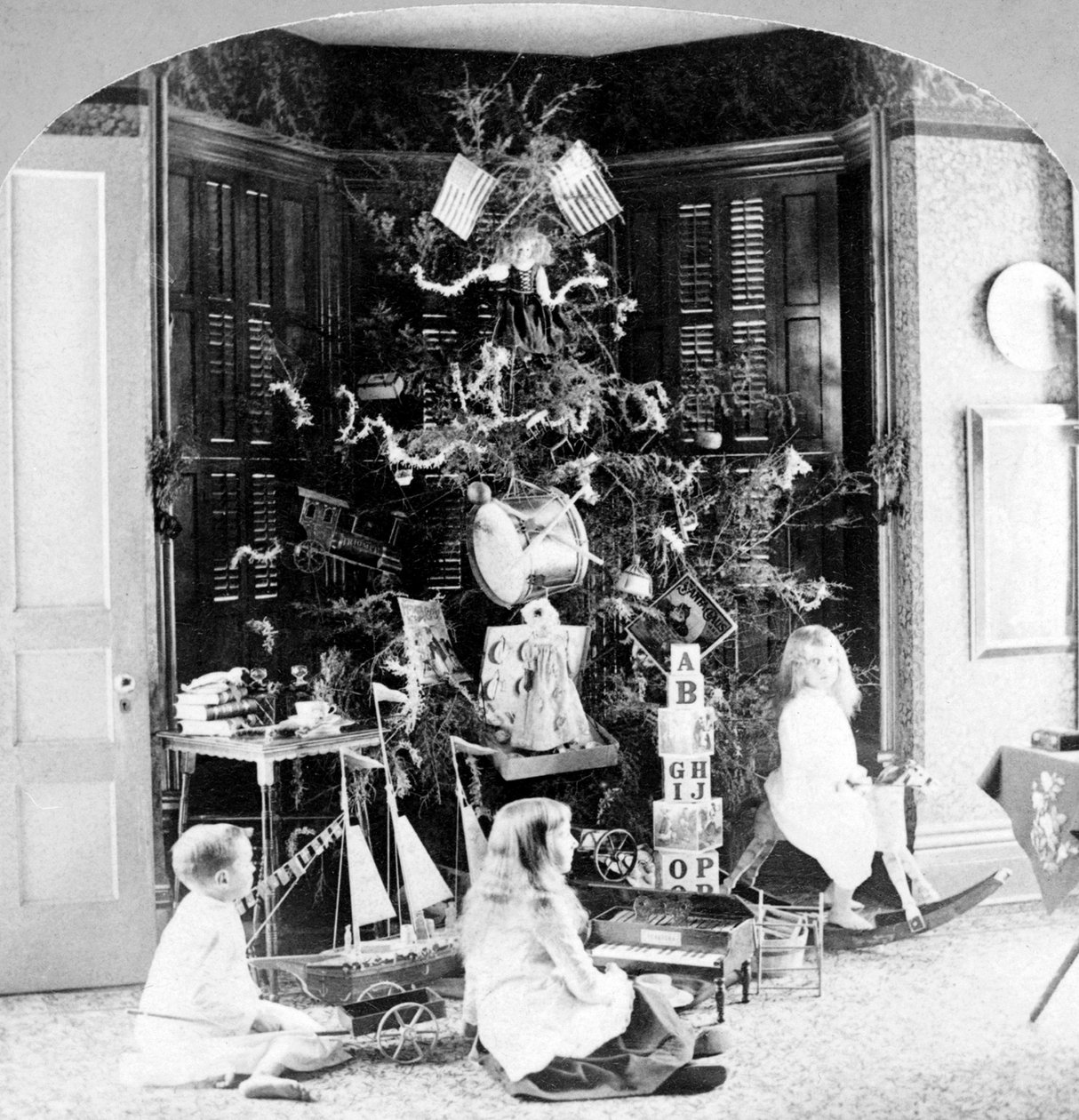 Børn samledes ved foden af træet omgivet af gaver julemorgen. af Unknown photographer