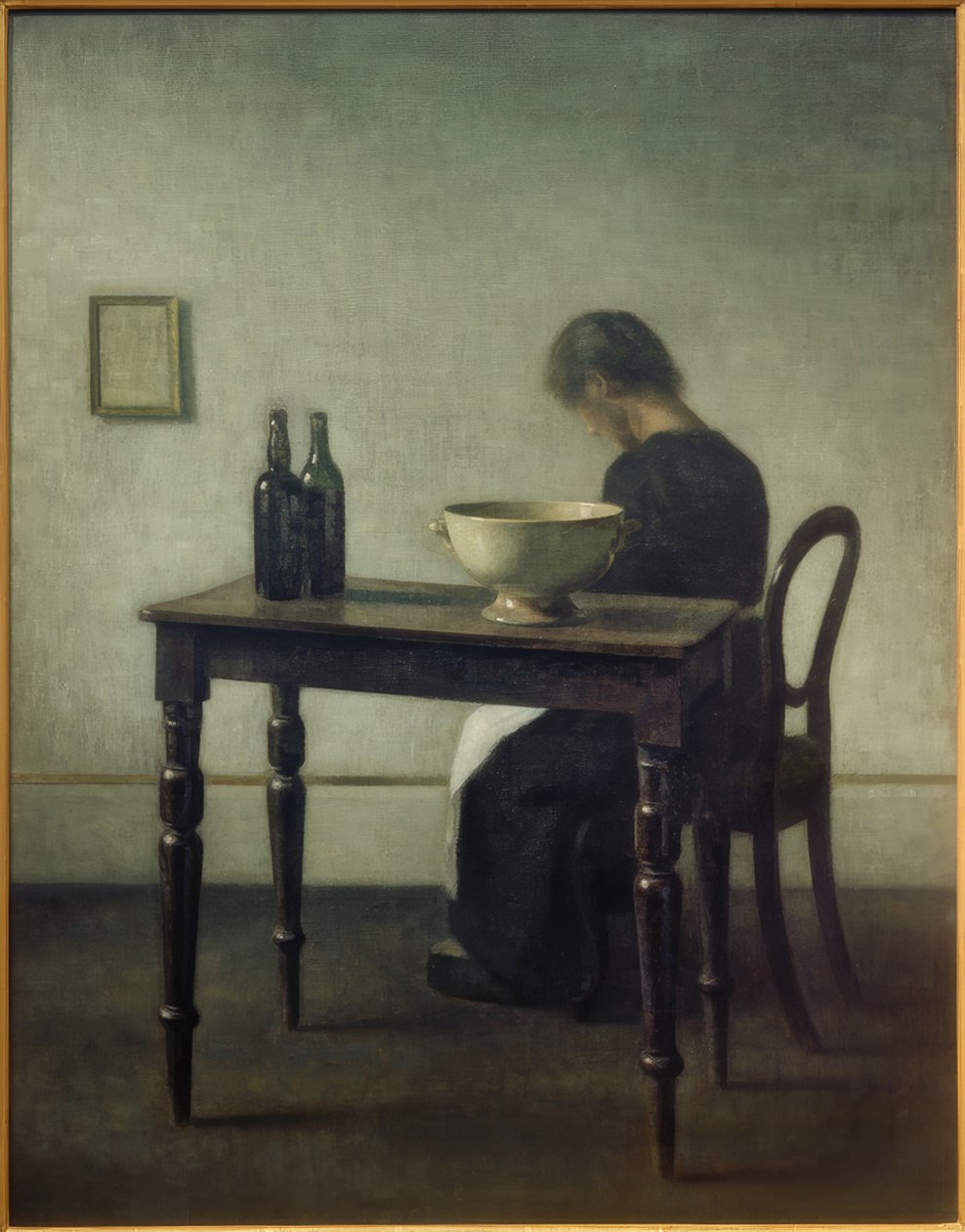 Kvinde sidder bag et bord af Vilhelm Hammershoi