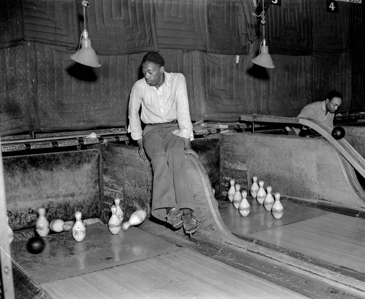 Afroamerikansk mand deltager i ti kegler på bowlingbane, for manuelt at nulstille keglen... af Volkmar Wentzel