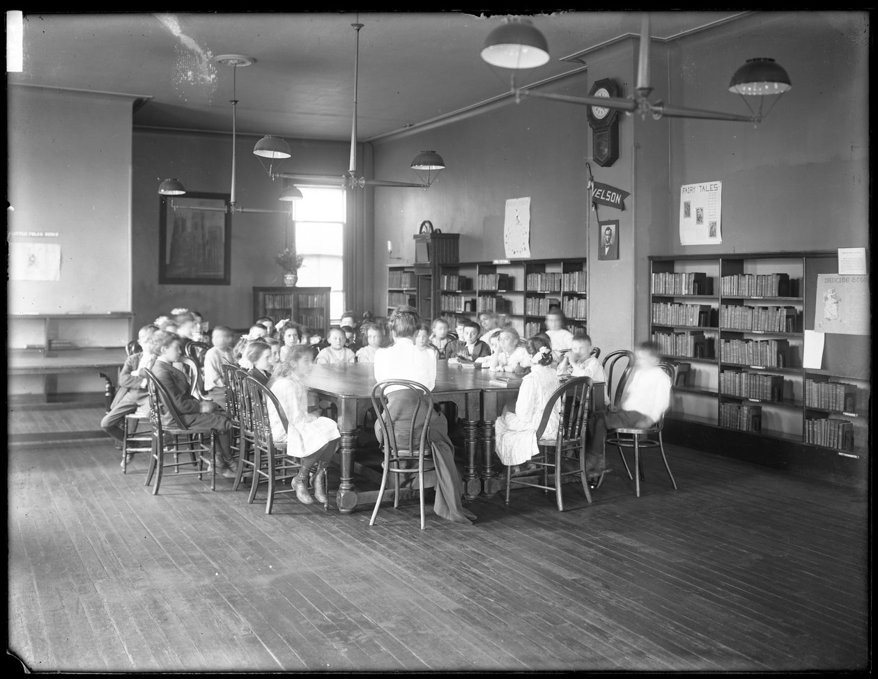 Børn lytter til en kvinde i læsesalen i en uidentificeret afdeling af Queens Borough Public Library, ca. 1910 (s/h-foto) af William Davis Hassler