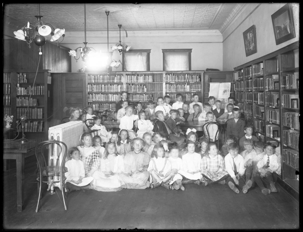 Gruppeportræt af børn i læsesalen i en uidentificeret afdeling af Queens Borough Public Library, ca. 1910 af William Davis Hassler