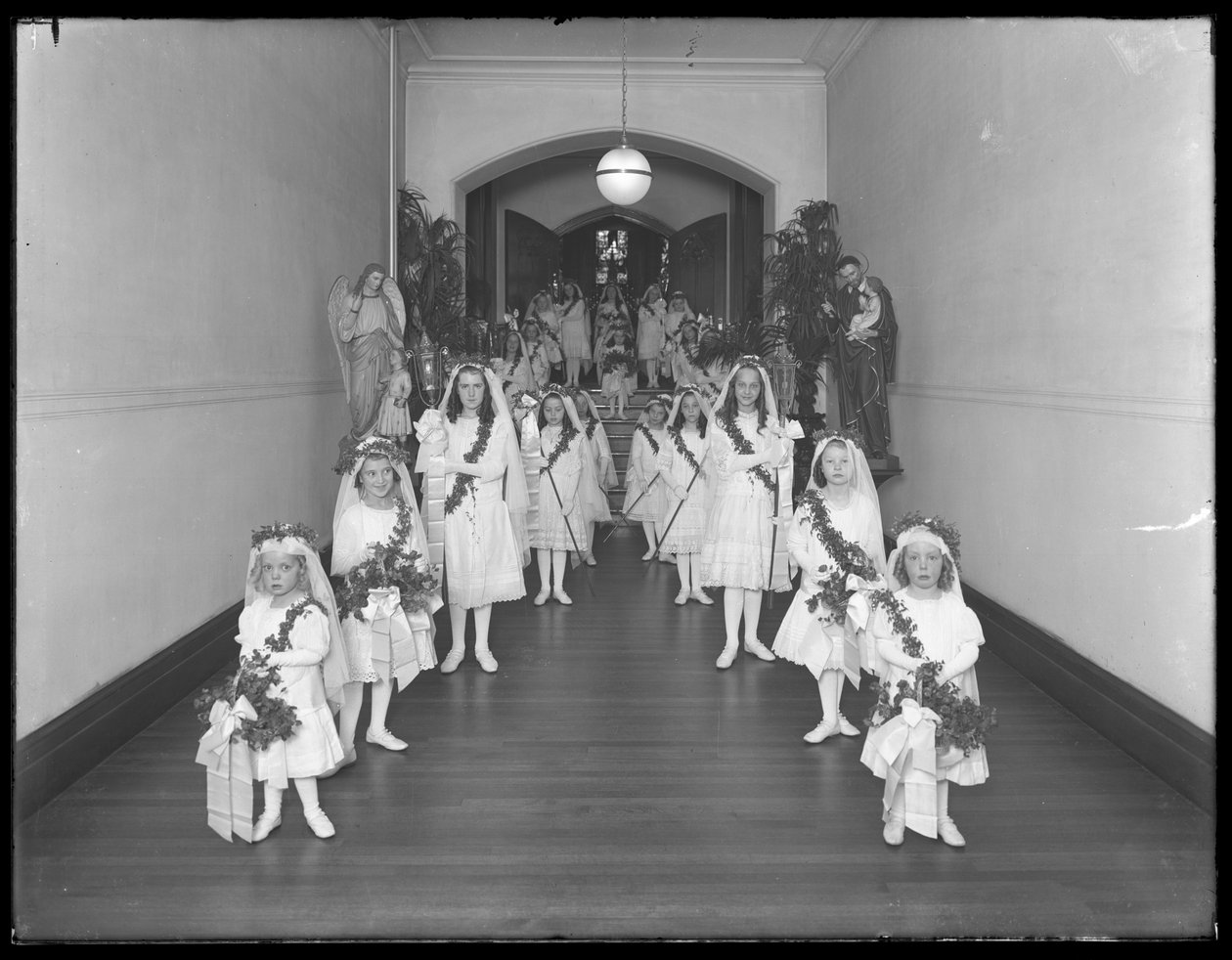 Små piger på The Roman Catholic Orphan Asylum, Kingsbridge, Bronx, vender tilbage fra kapellet i hvide kjoler med kranse og guirlander, 20. oktober 1914 af William Davis Hassler