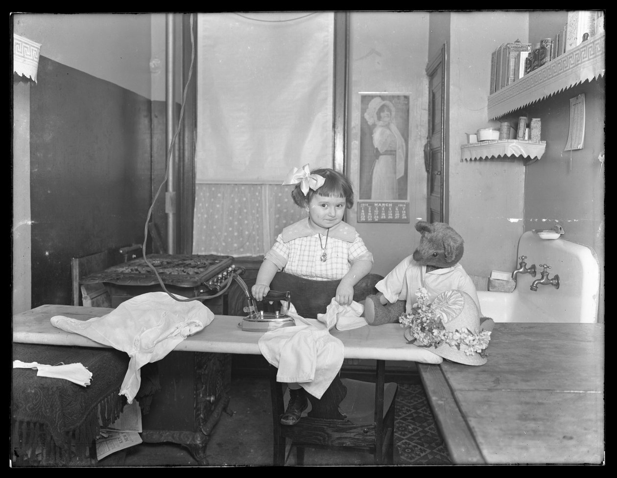 Uidentificeret lille pige demonstrerer brugen af et elektrisk strygejern, ca. 1913-14 af William Davis Hassler