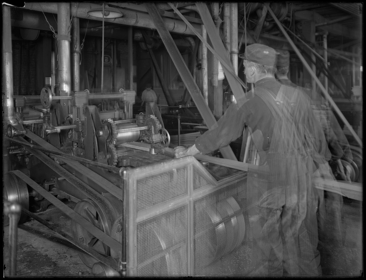 Arbejder fodrer tømmer ind i en høvlemaskine, Oneida, New York, 3. april 1916 af William Davis Hassler