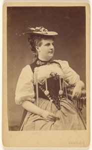 [Uidentificeret kvinde i indianerkostume med hat, siddende]. af A. Gabler